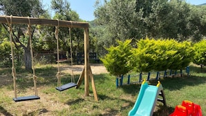 Un parque infantil con un columpio, un tobogán y una estructura roja para jugar.
