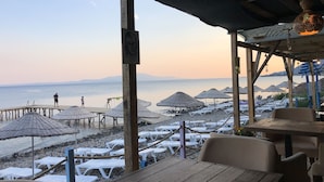 Un restaurante frente a la playa con terraza, sombrillas y vistas al mar.