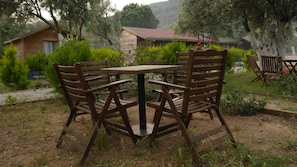 A rustic wooden table and chairs in a garden setting with a house in the background.