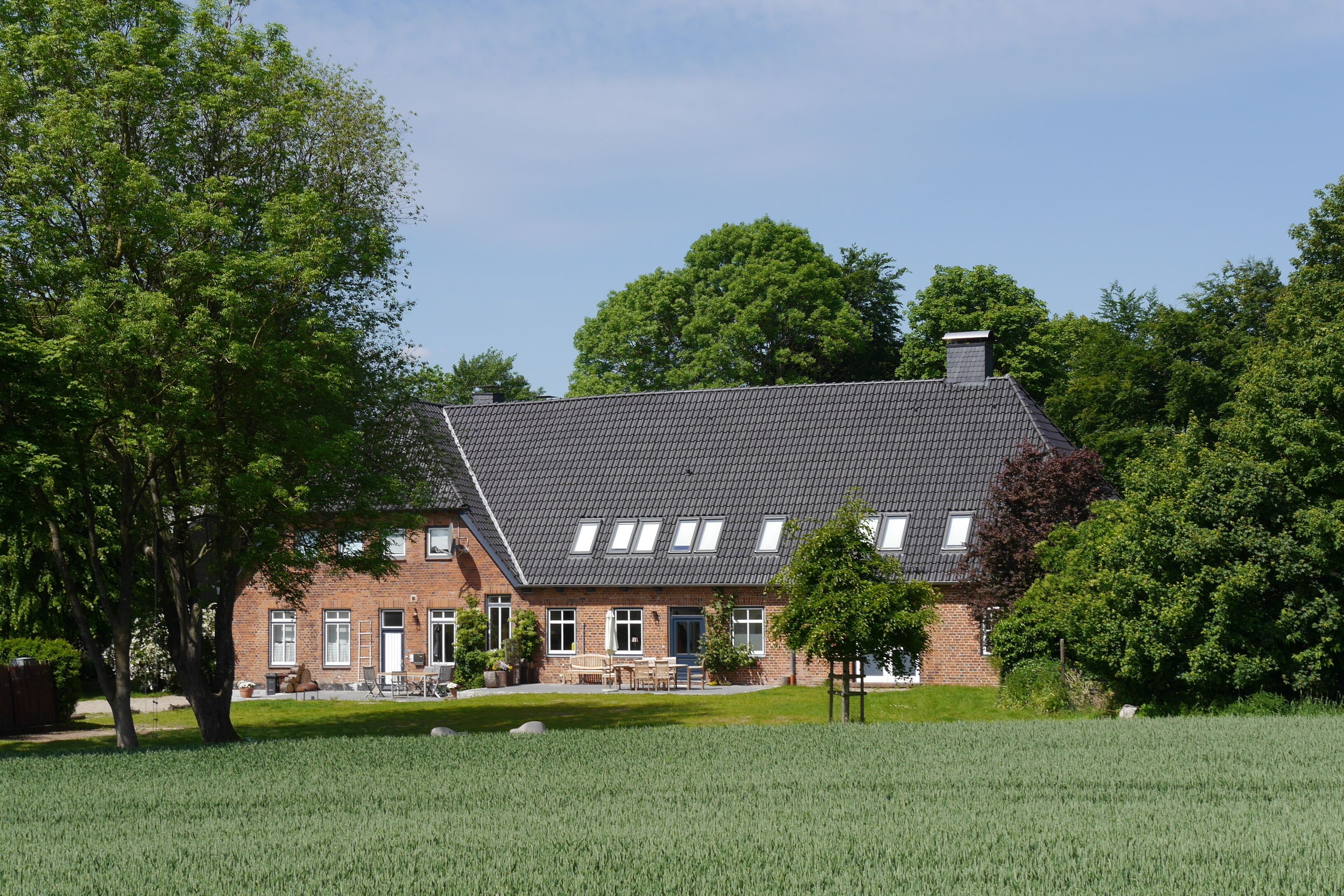 A two-story brick building with a sloped roof, multiple windows, and a well-maintained lawn.