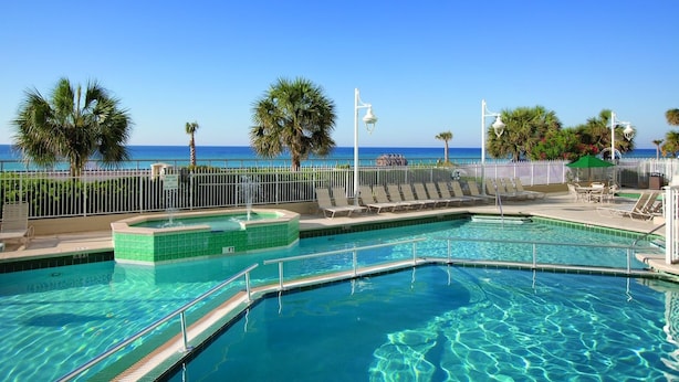 A pool area with clear blue water, a palm tree, and a view of the ocean. - Two Bedroom Deluxe Luxury Condo, Destin Florida (1985476) (Destin)