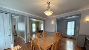 A dining area with a wooden table and chairs, a chandelier, and a view of a kitchen and dining room through an open door. - WATKINS GLEN GUEST HOUSE, CLOSE TO EVERYTHING! (Watkins Glen)