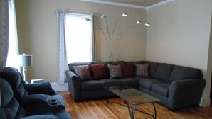 A living room with a sectional sofa, a glass coffee table, and a floor lamp. - WATKINS GLEN GUEST HOUSE, CLOSE TO EVERYTHING! (Watkins Glen)