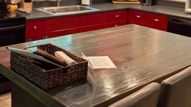 Una cocina moderna con armarios rojos, una isla central e iluminación colgante.