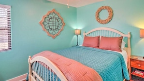 Un dormitorio con cama, ventilador de techo, decoración en la pared y mesita de noche.