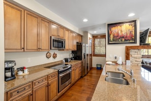Enjoy cooking in this well-lit kitchen with a granite countertop, stainless steel appliances, and wooden cabinetry.