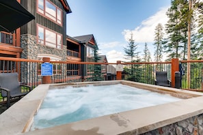 Relax in the spa area with a hot tub surrounded by a deck and stone wall.