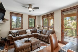 Relax in the living area with a large L-shaped sofa, flat-screen TV, and dining table.