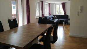 Un salon moderne avec une table à manger en bois, un canapé en cuir noir et des chaises assorties.