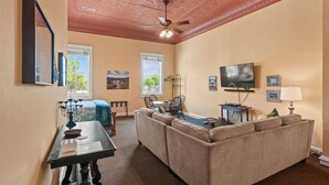 A living room with a ceiling fan, a television, a sofa, and a dining table with chairs.