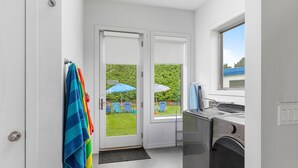A laundry room with two doors leading to a backyard, a washing machine, and a dryer. - Douglas Modern Villa - Steps to Downtown! (Douglas)