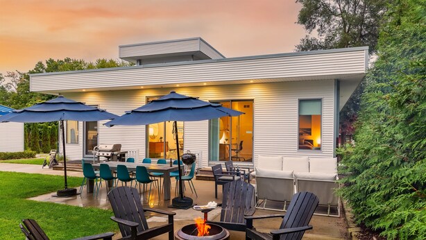 A modern house with a patio area featuring outdoor furniture, a fire pit, and umbrellas. - Douglas Modern Villa - Steps to Downtown! (Douglas)
