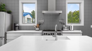 A modern kitchen with a central island, a stove, and two windows. - Douglas Modern Villa - Steps to Downtown! (Douglas)