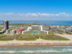 A coastal resort with beachfront villas, a marina, and a beach with umbrellas. - Saida II #205 | Beachfront Condo • 3 Pools • Direct Beach Access (South Padre Island)