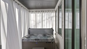 Un espace bien-être comprenant un jacuzzi, un petit marchepied et une fenêtre avec des stores.