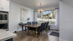 Une cuisine moderne avec une table à manger en bois, des chaises noires et un four en acier inoxydable.