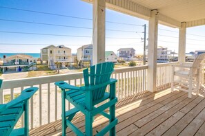 A wooden deck with chairs, overlooking a beach with houses. - Beaches B Tripp'n - Awesome 4 BR Home - Ocean View and Elevator! (North Topsail Beach)