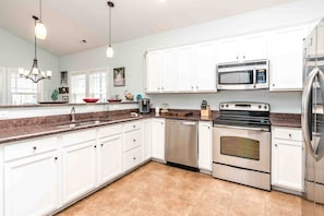 A modern kitchen with white cabinetry, stainless steel appliances, and a granite countertop.