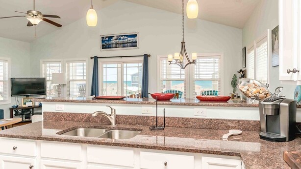 A spacious kitchen with granite countertops, a double sink, a coffee machine, and a large window with a view.
