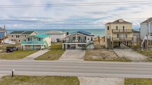 A coastal residential area with houses, a road, and a beach in the background.