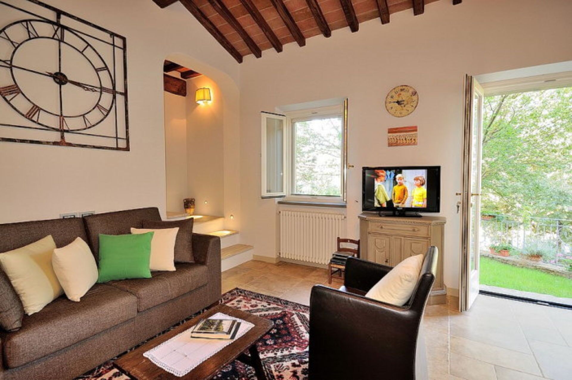 A living room with a sofa, a coffee table, a television, and a window.