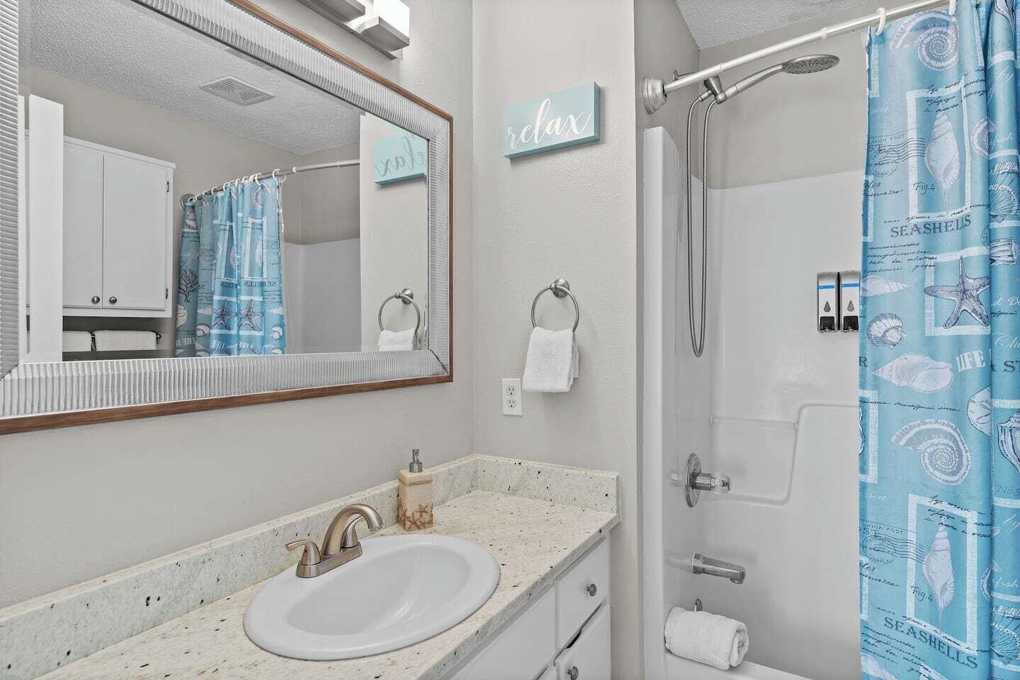 A bathroom with a sink, mirror, towel rack, and shower curtain.