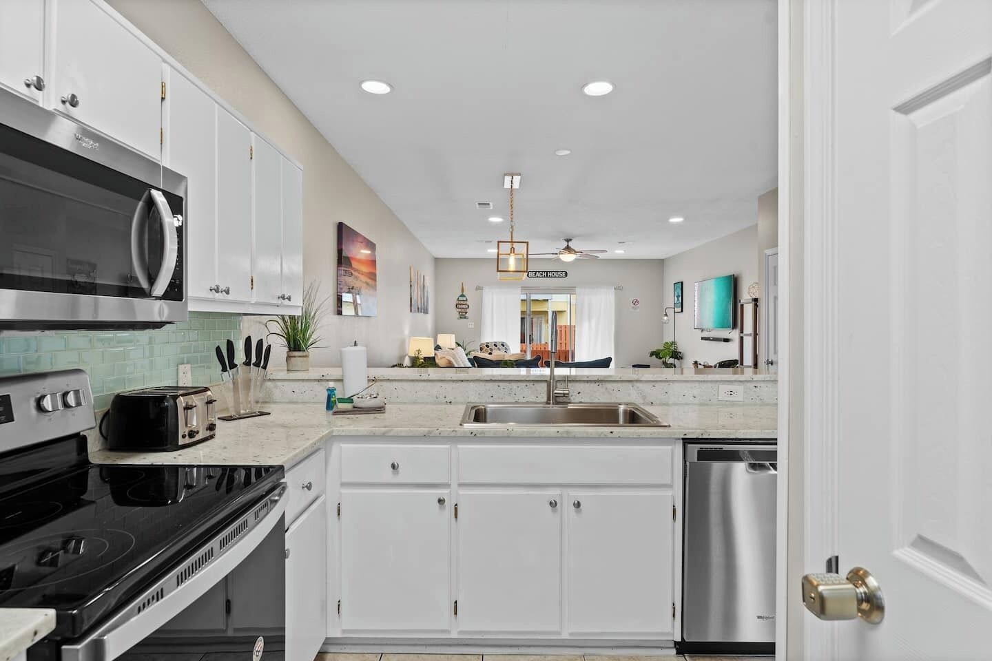 A modern kitchen with white cabinets, stainless steel appliances, and a central island with a sink.