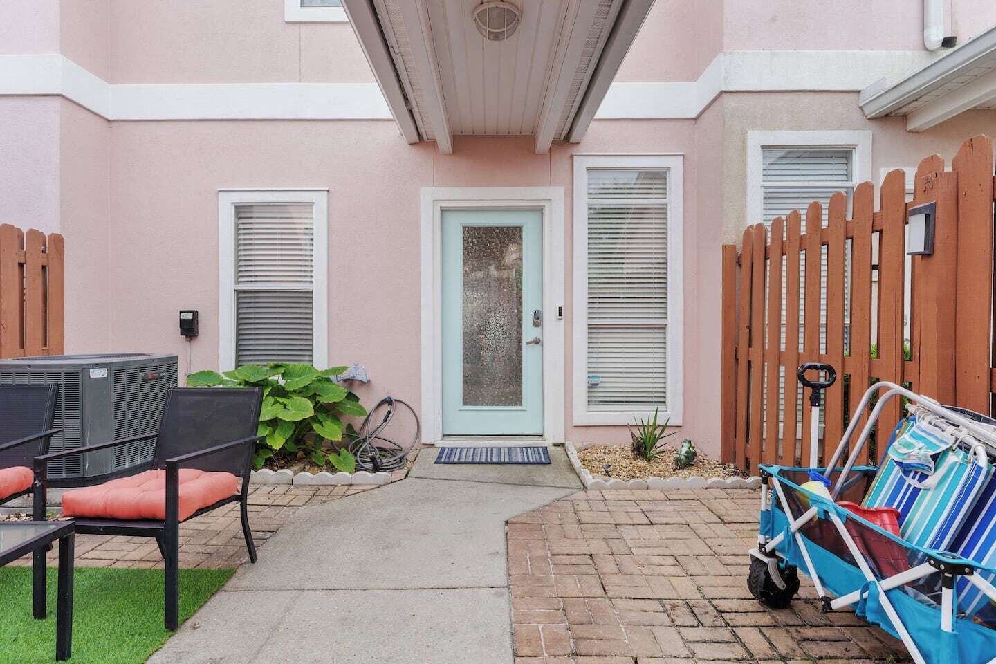 Eine Terrasse mit Tisch und Stühlen, ein kleiner Garten und ein Holzzaun.
