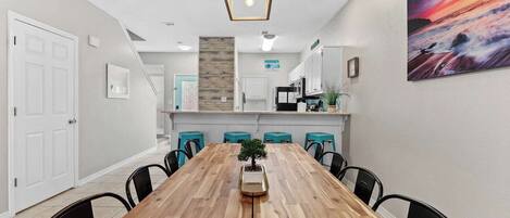 A modern dining area with a wooden table, black chairs, and a potted plant.