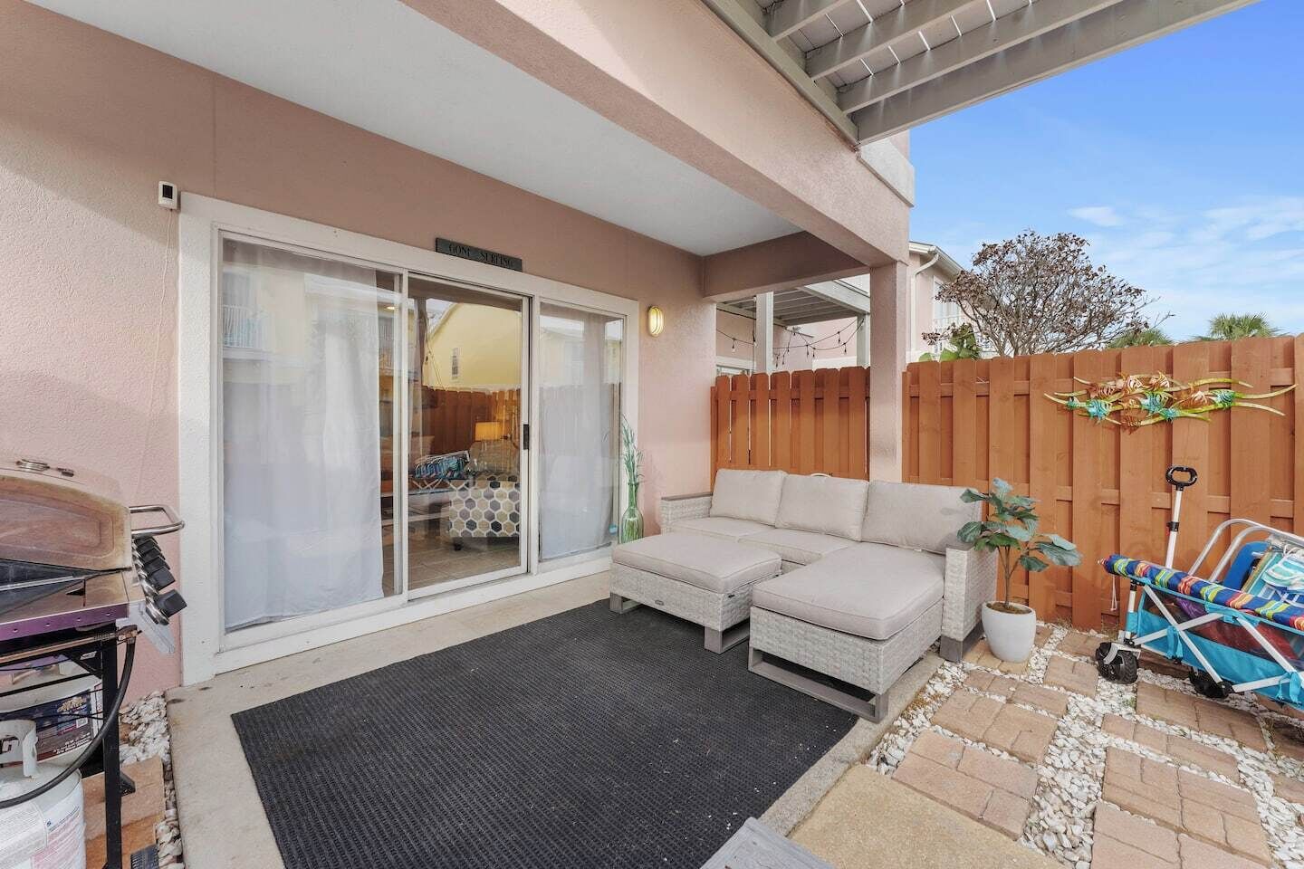 Un patio couvert avec une porte-fenêtre coulissante donnant sur un salon, un coin salon confortable et un barbecue.