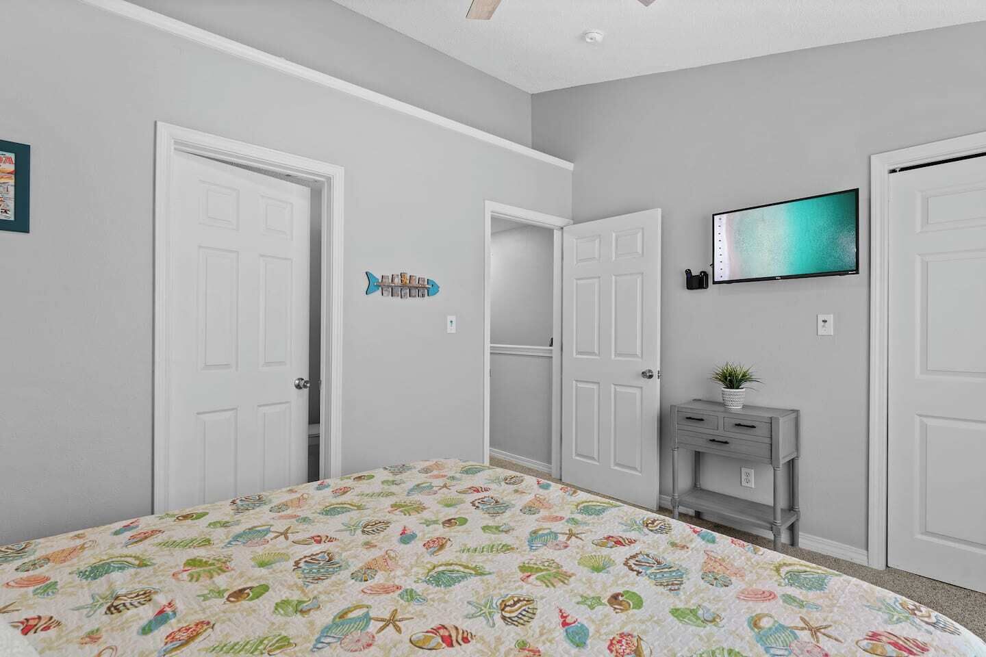 A bedroom with a bed, a TV, a dresser, and a door.