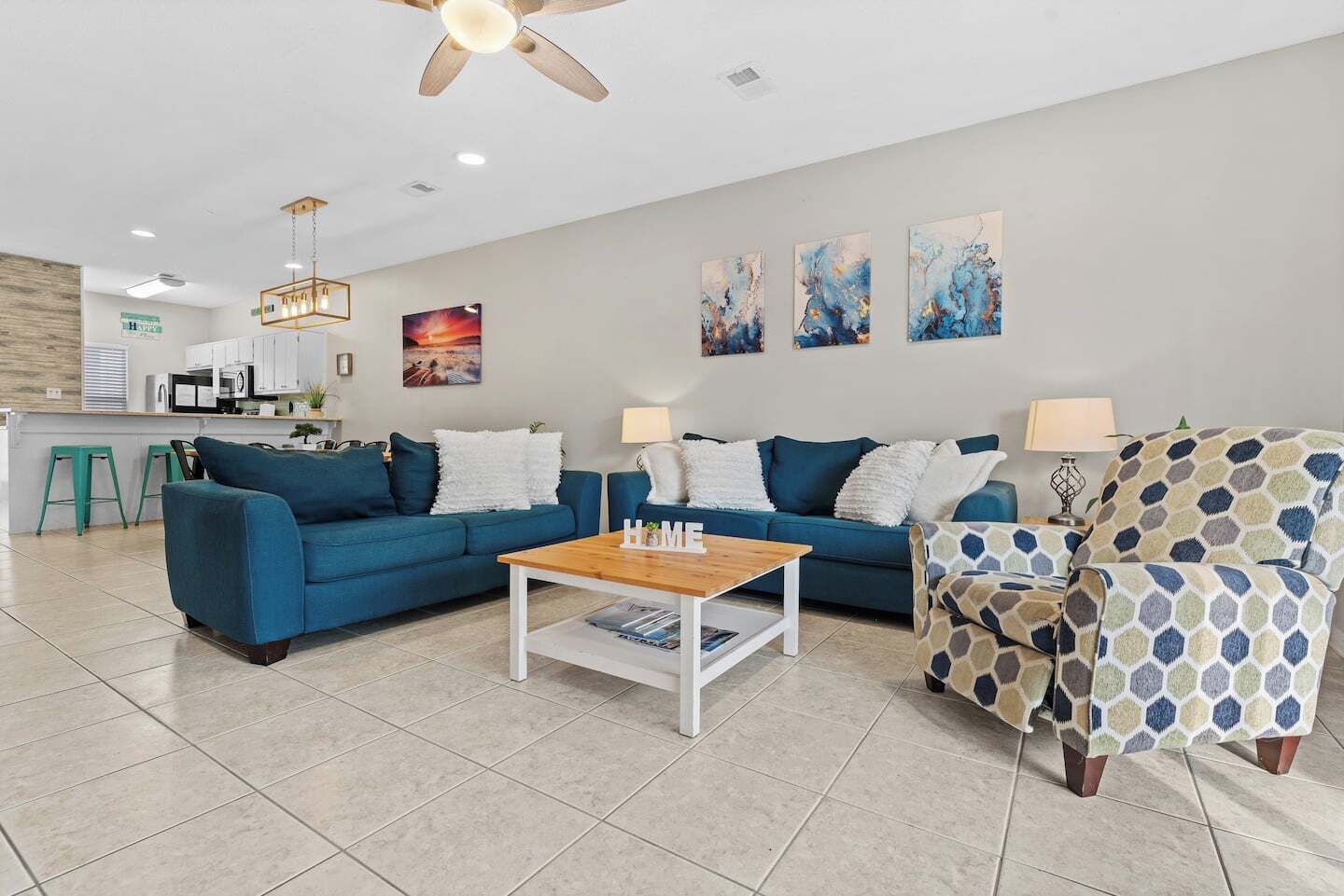 A modern living room with a blue sofa, a wooden coffee table, and patterned armchairs.