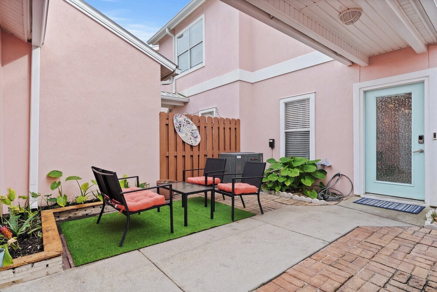 A patio with a table and chairs, a wooden fence, and a door with a frosted glass panel.