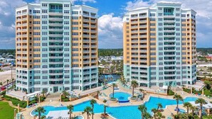 Ein Hochhaus-Hotel mit mehreren Balkonen, einem zentral gelegenen Swimmingpool und einer begrünten Poolanlage.