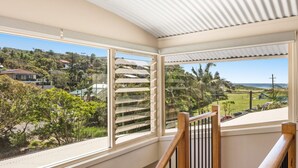 Una habitación con un amplio ventanal que da a una zona residencial con casas, vegetación y una playa.
