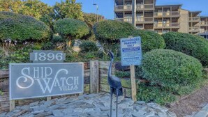 Segnaletica per Ship Watch Villas con una targa '1896', un cartello di parcheggio e una statua decorativa a forma di uccello.