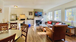 A modern kitchen with white cabinets, a built-in oven, and a flat-screen TV mounted above the fireplace. - PRIVATE Entrance, Mountain View ,2 BR/1.5 BT  (Harvie Heights)