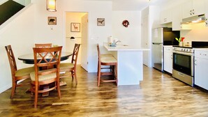 A modern kitchen with white cabinets, a built-in oven, and a dining area with wooden chairs and a table. - PRIVATE Entrance, Mountain View ,2 BR/1.5 BT  (Harvie Heights)