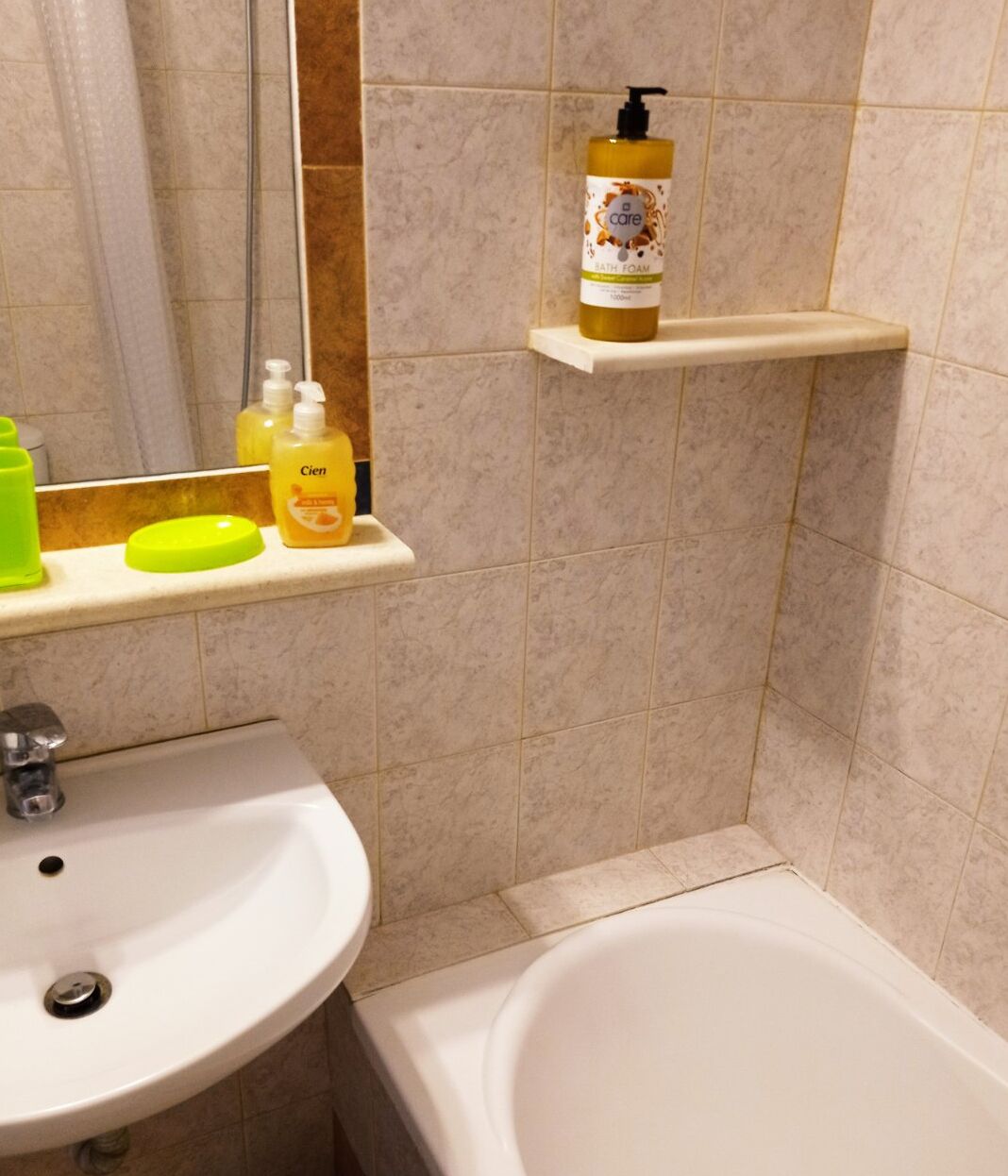 A bathroom with a sink, a bathtub, and shelves holding toiletries.