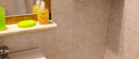 A bathroom with a sink, a bathtub, and shelves holding toiletries.