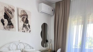 A bedroom with a bed, a chair, a desk, and artwork on the wall. - Julia Holiday Apartments (Zakynthos)