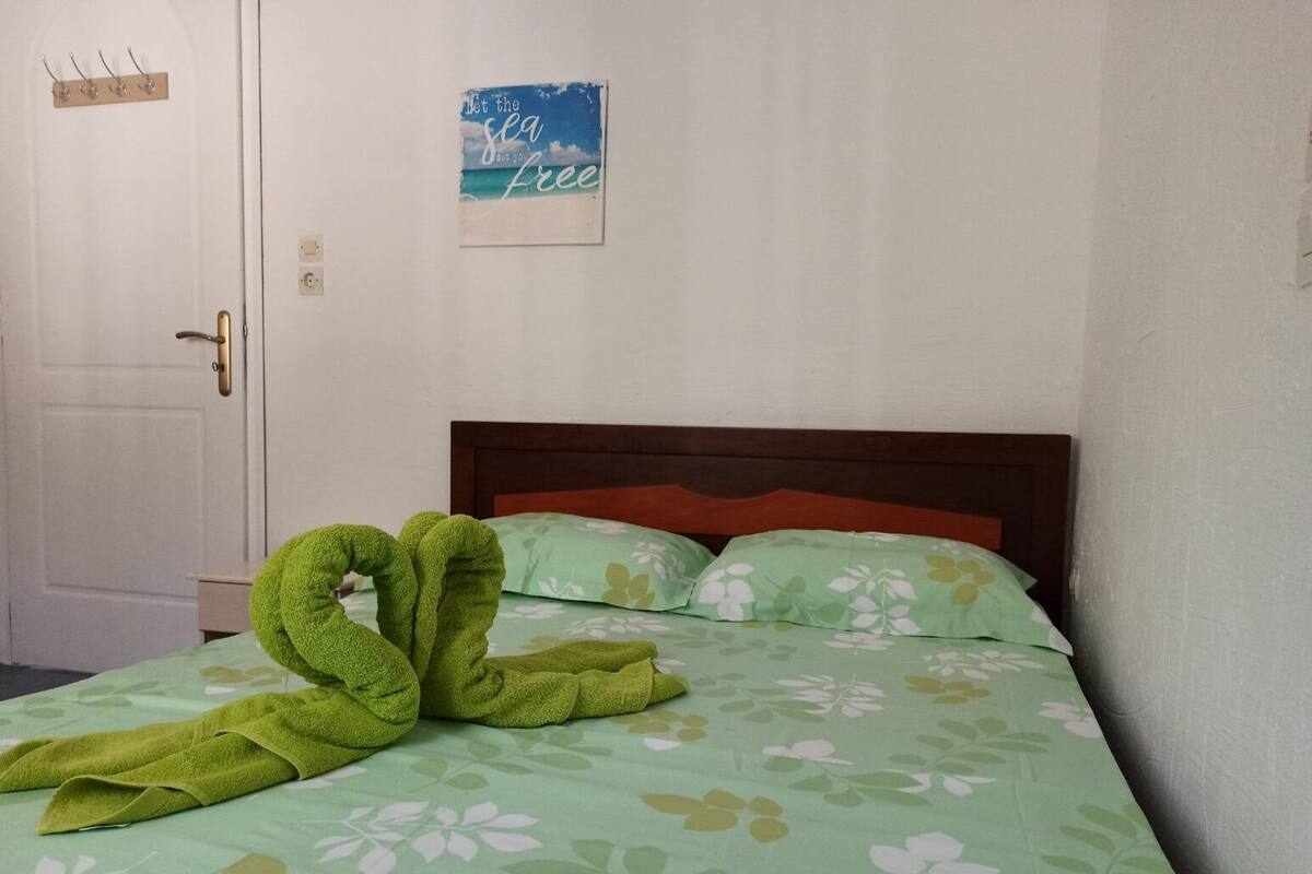 Un dormitorio con cama, una toalla verde y un adorno en la pared.