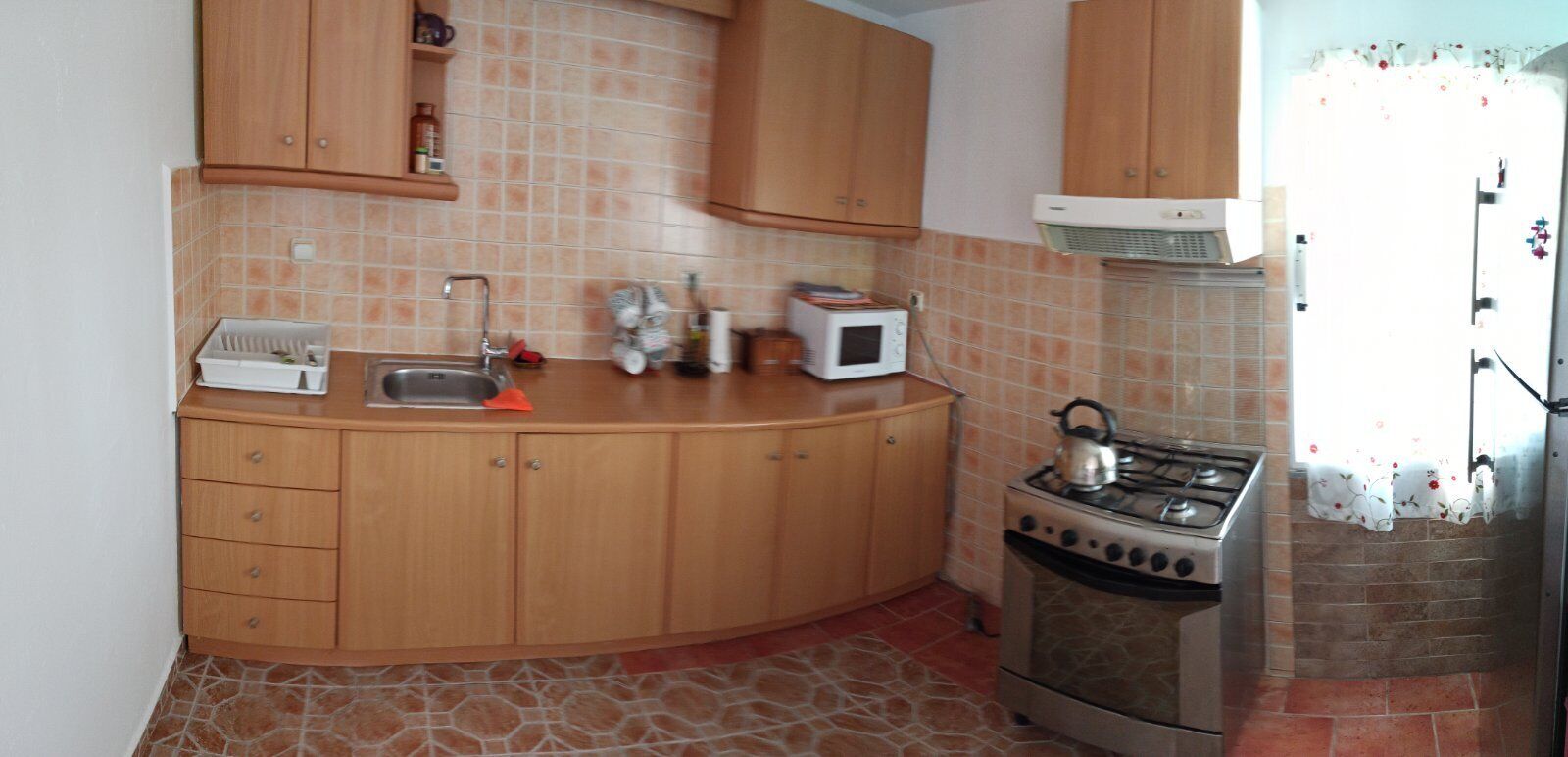 A kitchen with wooden cabinets, a gas stove, a microwave, and a sink.