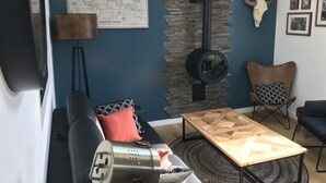 Un salon moderne avec un mur d’accent en pierre, une carte, une grande décoration représentant un crâne de taureau et une cheminée.