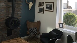 Un salon moderne avec une lucarne, un mur en pierre, une guitare et des tableaux encadrés.