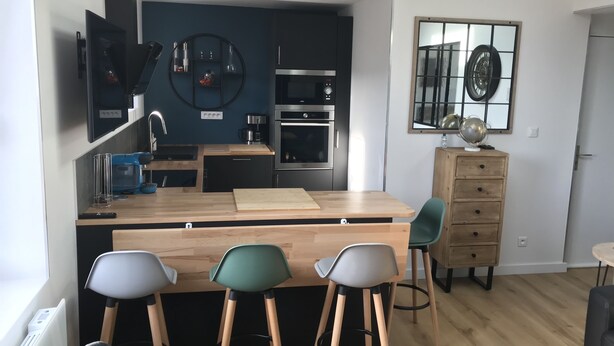 Une cuisine moderne avec un îlot central, des tabourets de bar et une table à manger.