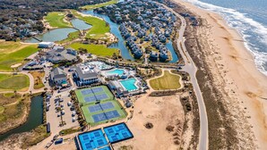 Vue aérienne d’une station balnéaire dotée de plusieurs piscines, de courts de tennis et d’un parcours de golf.
