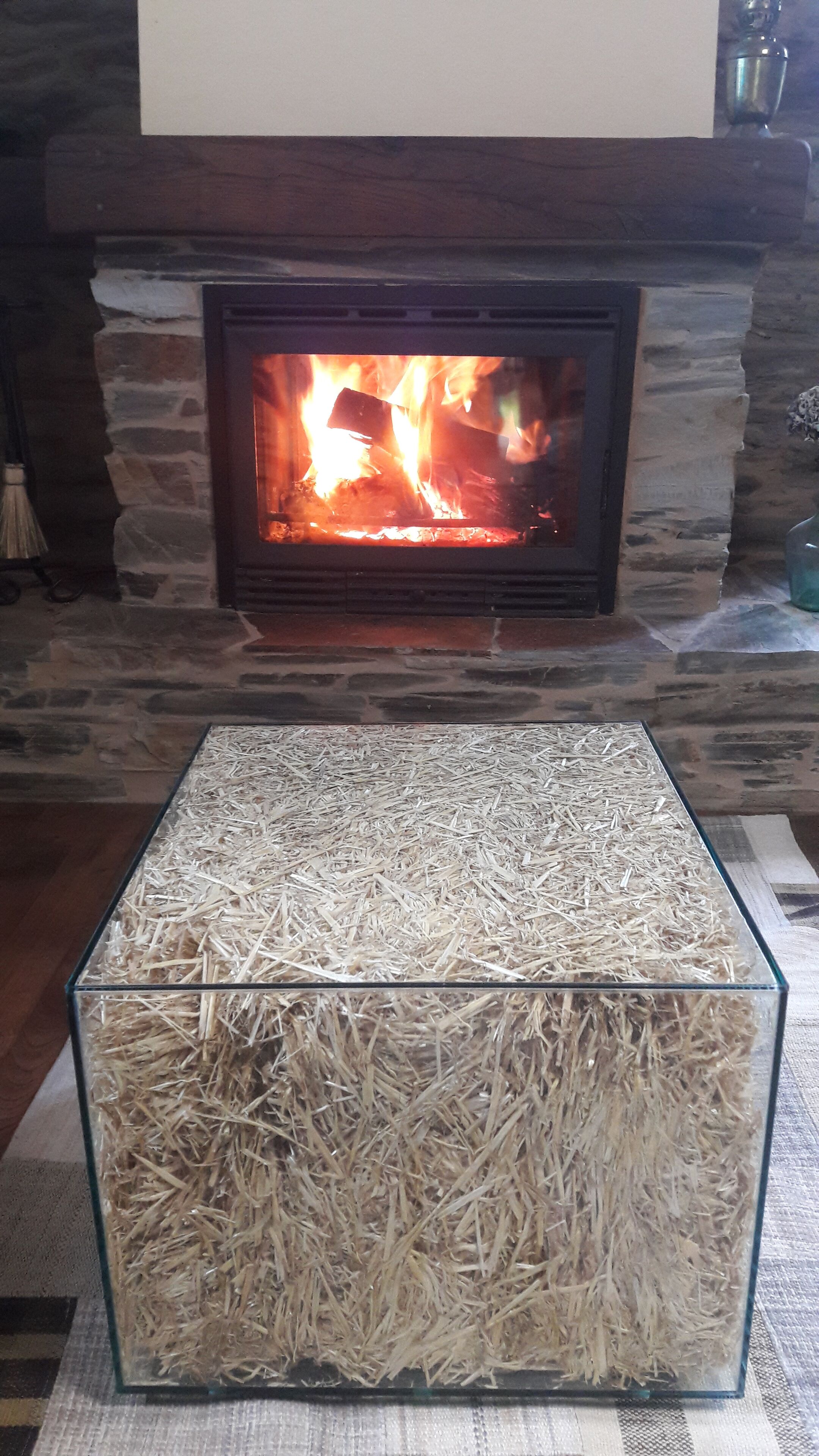 Una llar de foc amb un marc de pedra i una taula de vidre al davant.