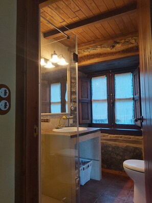 A bathroom with a wooden ceiling, a sink with a mirror, and a window with curtains. - Tourist use housing (Lugo)
