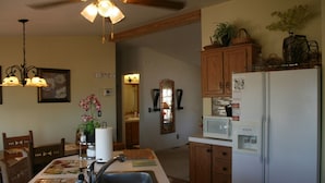 Une cuisine avec des meubles de rangement en bois, un réfrigérateur blanc, un four à micro-ondes, un évier et un ventilateur de plafond.
